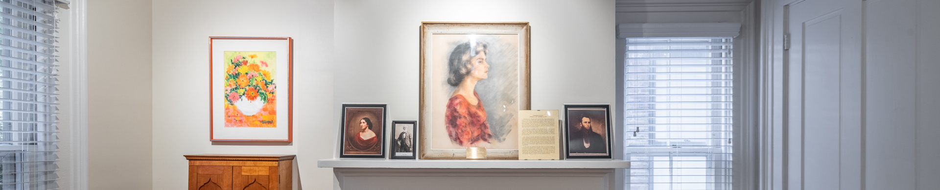 Interior display with framed portraits and artwork on a mantel